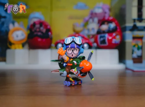 "WCF Scale Airplane Arale Dr. Slump statue. Iconic Arale figure in playful pilot pose on whimsical plane, detailed sculpture from a dynamic angle."