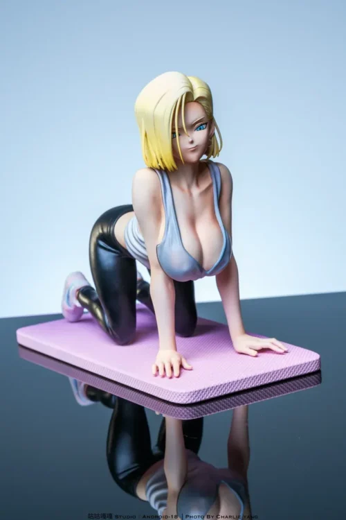 Playful Android 18 figure in a yoga pose stretches on a pink mat, wearing glossy black leggings, with a detachable mat for display.